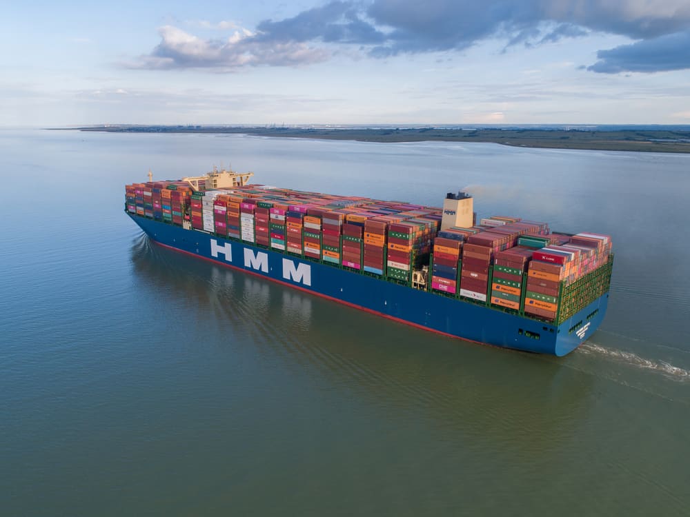 A container ship operated by HMM (Hyundai Merchant Marine) navigating the Thames River, England