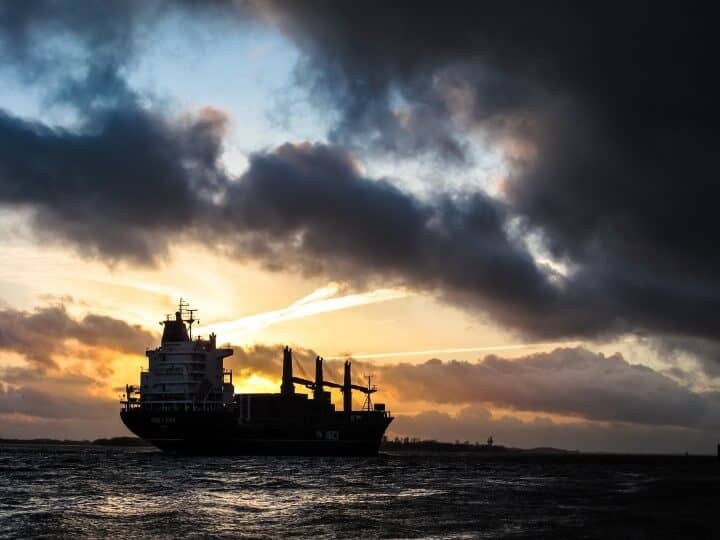 A container ship at sea at sunset.