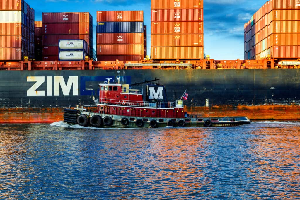 Ein kleines Boot fährt neben einem von ZIM betriebenen Containerschiff in Savannah, Georgia, vorbei